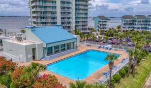 A hotel with a large swimming pool, multiple balconies, and a view of the ocean.