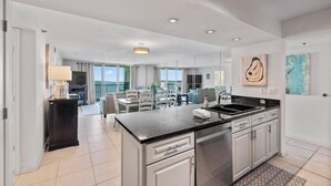 A modern kitchen with a black countertop, white cabinets, and a dining area with a table and chairs.