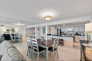 A modern kitchen with white cabinets, a central island, and a dining area with a wooden table and chairs.