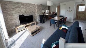 A modern living room with a TV, sofa, and dining area.