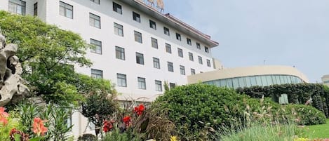 A multi-story hotel with a landscaped garden in front.