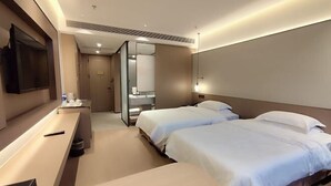 Camera d'albergo con due letti, una scrivania, una televisione e bagno visibile tramite una porta in vetro.
