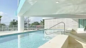 Una piscina con vistas despejadas de los alrededores, incluyendo un edificio de diseño moderno y una barandilla alrededor de la piscina.