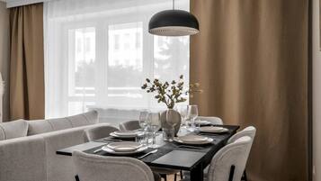 A dining area with a rectangular table set for four, a vase with flowers, and a pendant light.