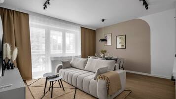 A modern living room with a sofa, a small round table, and a dining area with a table set for four.