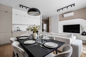 Un comedor moderno con una mesa negra para cuatro, sillas blancas y un florero con flores.