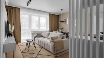 A modern living room with a sofa, a dining table, and a TV.
