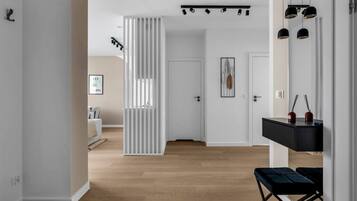 A modern interior with a wooden floor, a white partition, and a black bench.