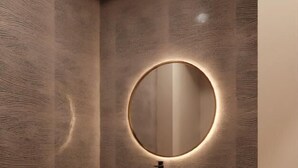 A modern bathroom with a wooden vanity, a round mirror with underlighting, and a small shelf with toiletries. - The Himalayan Tyangbouche (Milinggo)