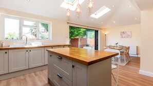 Une cuisine moderne avec des meubles gris, un plan de travail en bois et des luminaires suspendus.