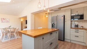 Une cuisine moderne dotée d’un îlot central en bois, d’appareils électroménagers en acier inoxydable et de luminaires suspendus.