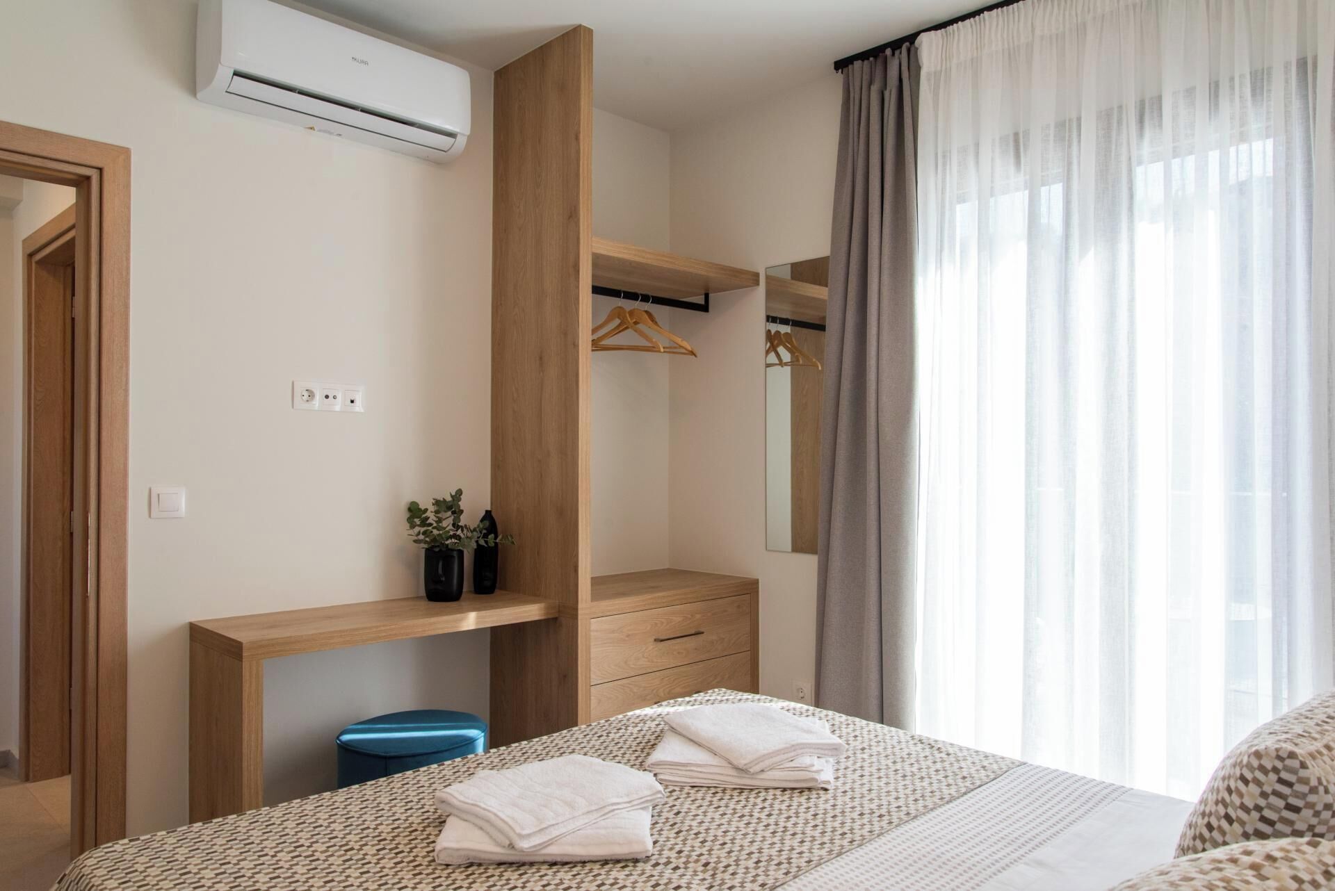 Ein modernes Schlafzimmer mit Bett, Nachttischen, einem Kleiderschrank, einem Spiegel und einem Fenster mit Vorhängen.