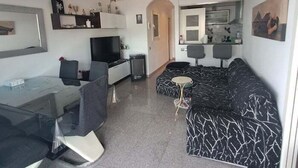 En moderne stue med sofa, spisebord og fjernsyn.