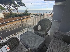 Ein Balkon mit Korbmöbeln, Meerblick und einem Metallgeländer.