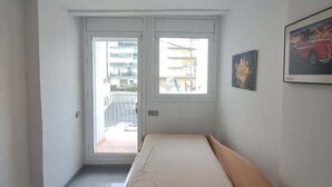 Et soveværelse med seng, et vindue og en dør, der fører ud til en balkon.