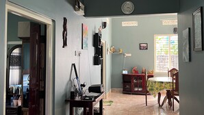 A spacious living area with a dining table, chairs, and a kitchen area in the background.