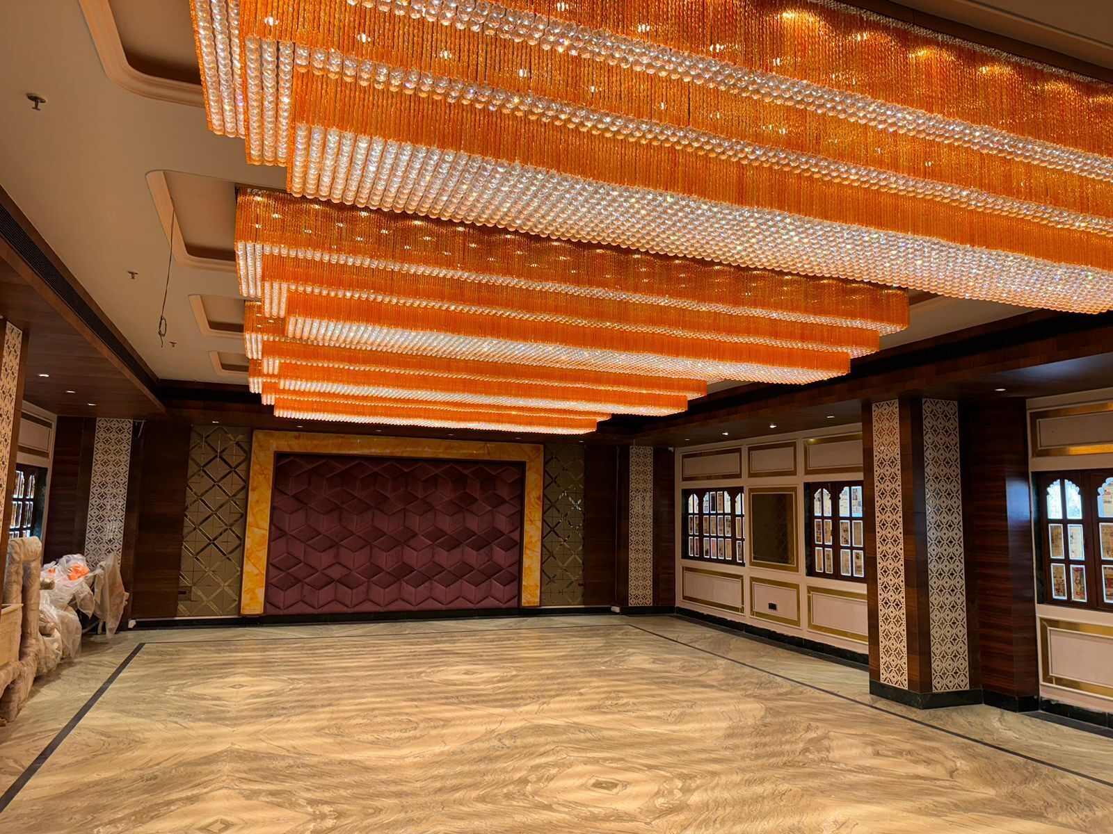 A spacious hall with a large, ornate chandelier and a patterned wall.