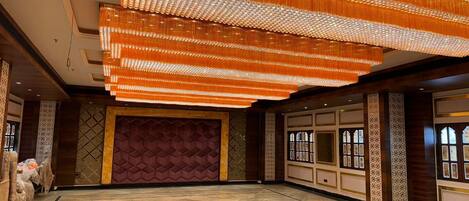 A spacious hall with a large, ornate chandelier and a patterned wall.