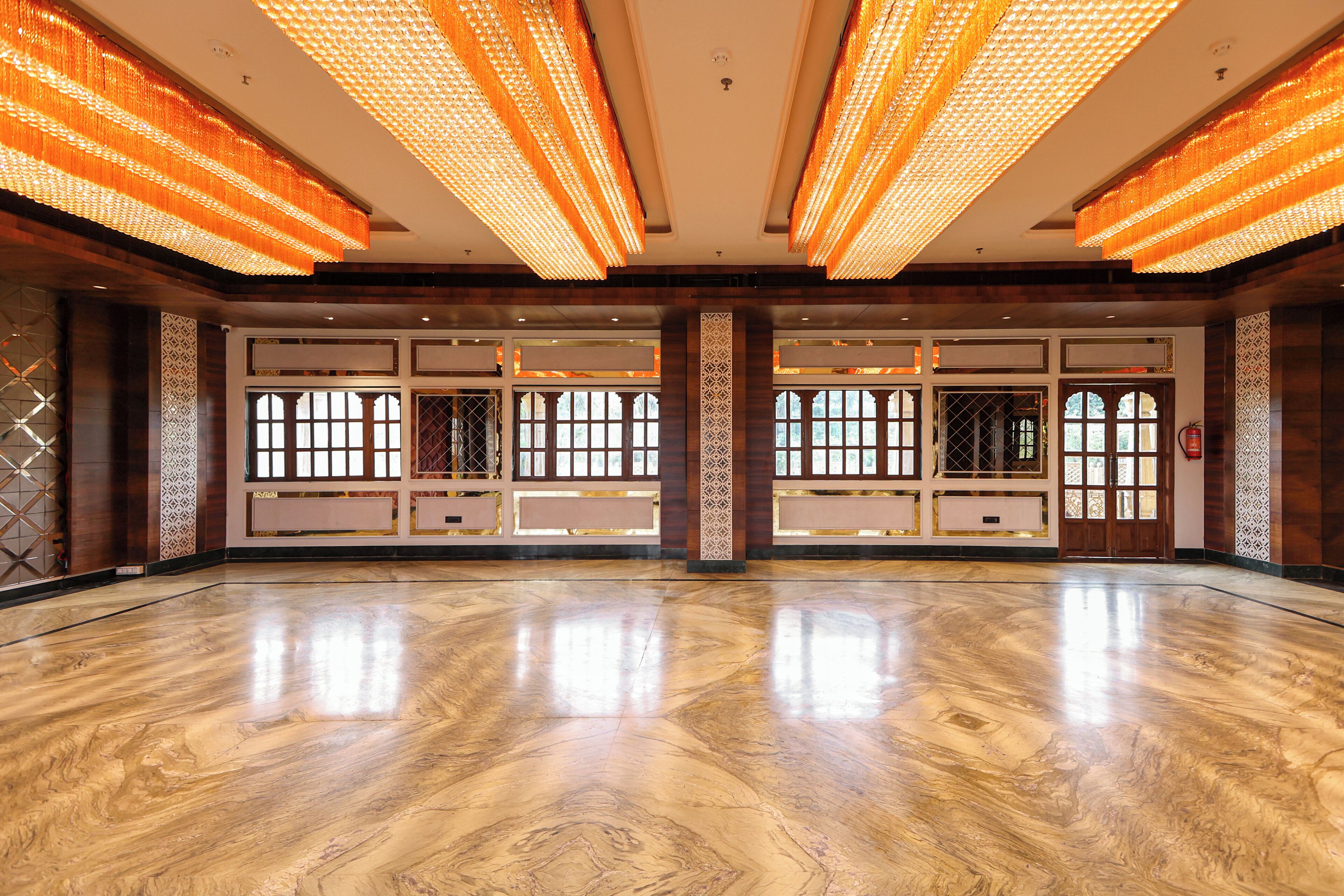 A spacious hall with a polished wooden floor, large windows, and modern lighting fixtures.