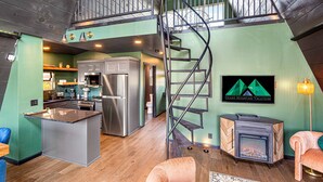 A spacious loft with a kitchen, dining area, and a fireplace. A spiral staircase connects the two levels. - Luxury Adults-Only A-Frames |Table Rock (Omaha)