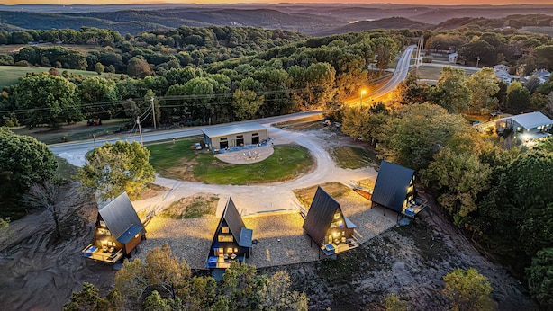 A remote, scenic area with a small lodge featuring multiple cabins, a central building, and a dirt road. - Luxury Adults-Only A-Frames |Table Rock (Omaha)