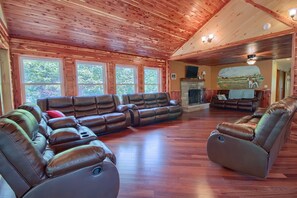 A spacious living room with a large sectional sofa, a fireplace, and a scenic mural on the wall.