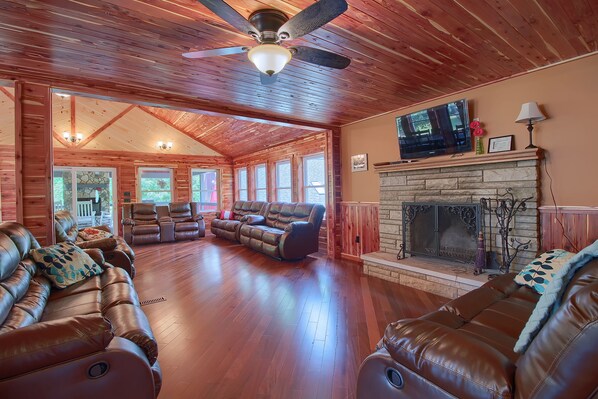 A spacious living room with leather sofas, a fireplace, and a television.
