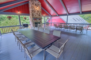 A covered outdoor patio with a stone fireplace, red ceiling, and a dining table with chairs.