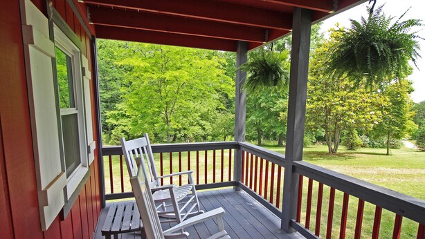 A covered porch with wooden benches and a red railing.