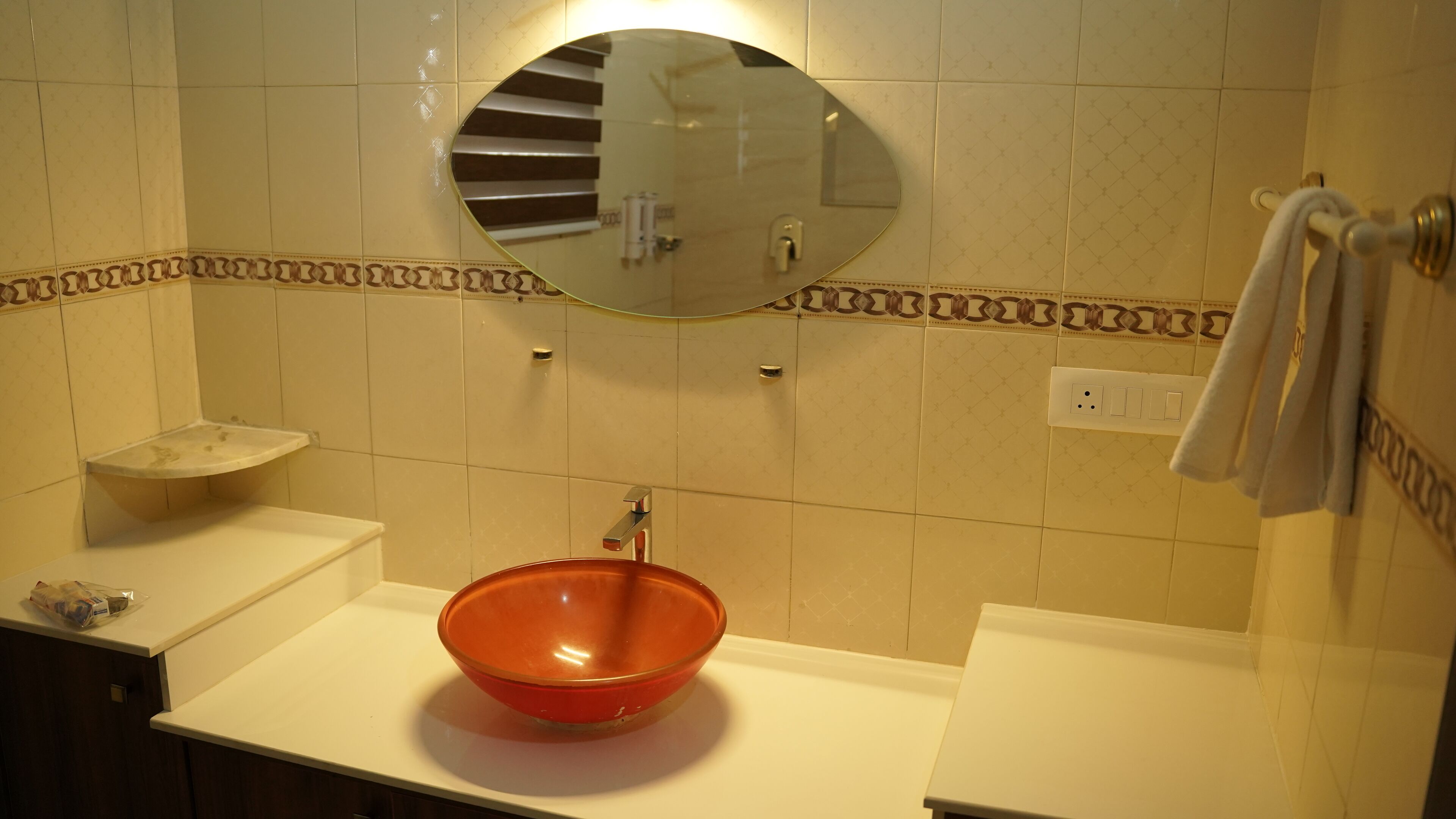 Un baño con un lavamanos blanco, un cuenco naranja, un espejo y un perchero para toallas.