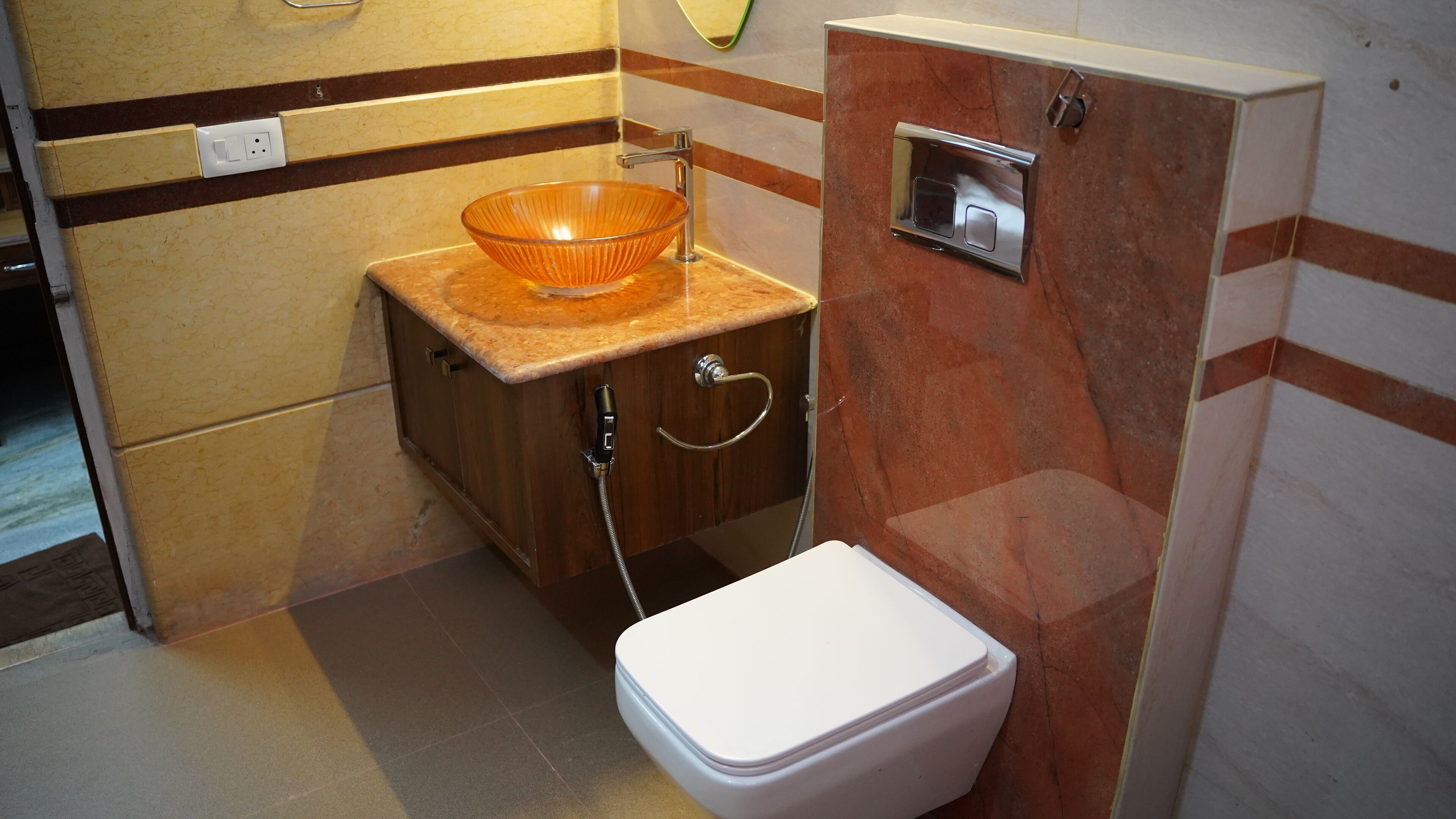 A compact bathroom with a glass bowl sink, a white toilet, and a shower with a handheld hose.