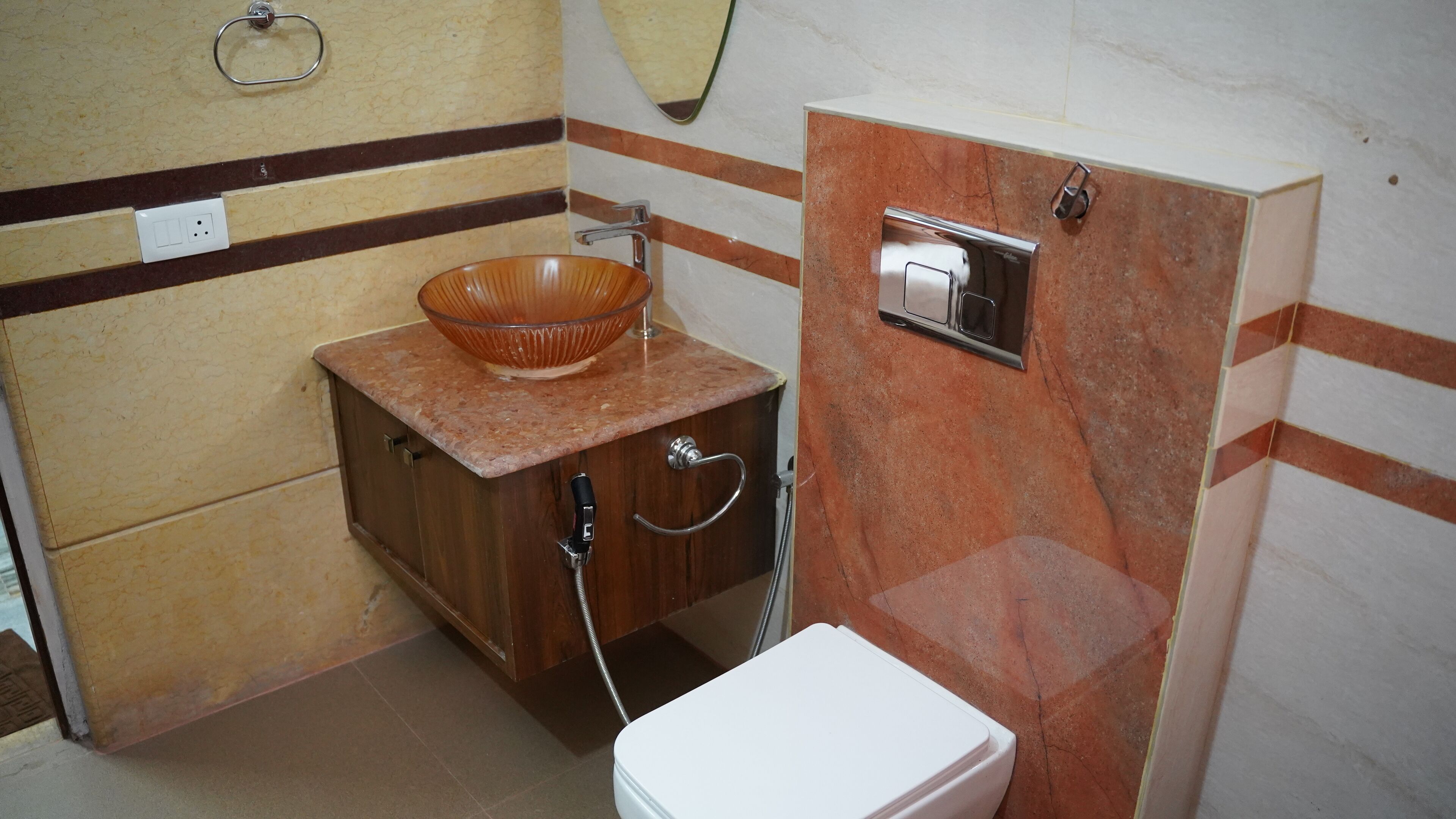 A bathroom with a wooden cabinet, a glass bowl sink, a toilet, and a shower.