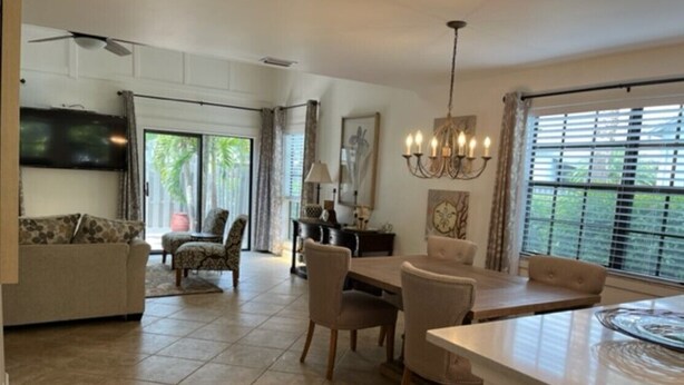 A spacious living room with a large TV, a dining area with a table and chairs, and a kitchen with a large island. - Fabulous Naples Townhouse in Desirable Pelican Ridge Location (Naples)