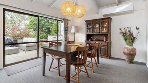 A dining area with a large table, wooden chairs, and a vase of dried plants. - Waiake Family Retreat - Auckland Holiday Home (Auckland)
