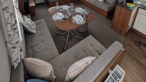 Un espace de vie compact comprenant un canapé, une table à manger pour quatre personnes et un coin cuisine.