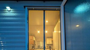 Une cuisine avec une porte coulissante donnant sur un espace de vie, un paillasson et un petit espace extérieur doté d’une rambarde.