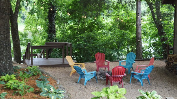 A covered outdoor seating area with Adirondack chairs and a wooden deck.
