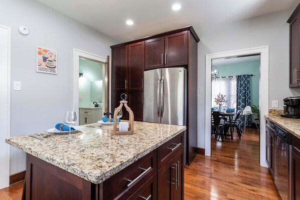 A modern kitchen with dark wood cabinets, a stainless steel refrigerator, and a granite countertop.
