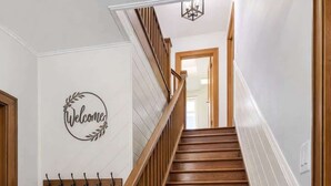 Una escalera de madera con un letrero que dice 'Welcome', un perchero y una planta en maceta.