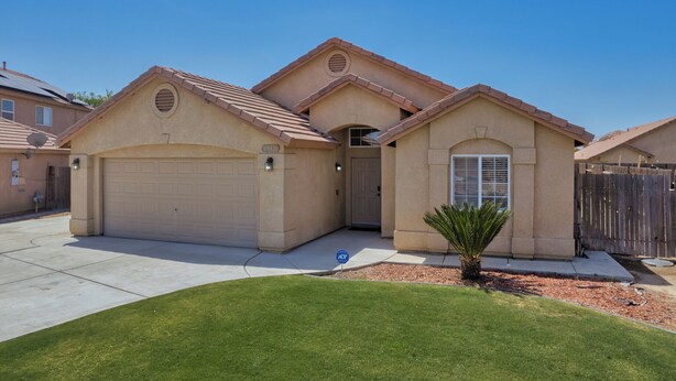 A two-story house with a garage, a covered entryway, and a small front yard with a palm tree. - Spacious Home Right off 99 Fwy (Bakersfield)