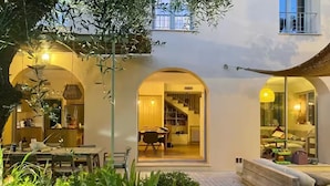 Une cour intérieure accueillante, avec un espace repas, un canapé et un escalier menant à un niveau supérieur.
