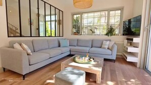 Un salon moderne avec un canapé d’angle gris, une table basse en bois et un grand téléviseur.