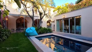 Une propriété résidentielle moderne dotée d’une piscine, d’un patio couvert et d’un jardin bien entretenu.