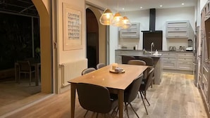 Une cuisine moderne avec des meubles blancs, un îlot central et des luminaires suspendus.
