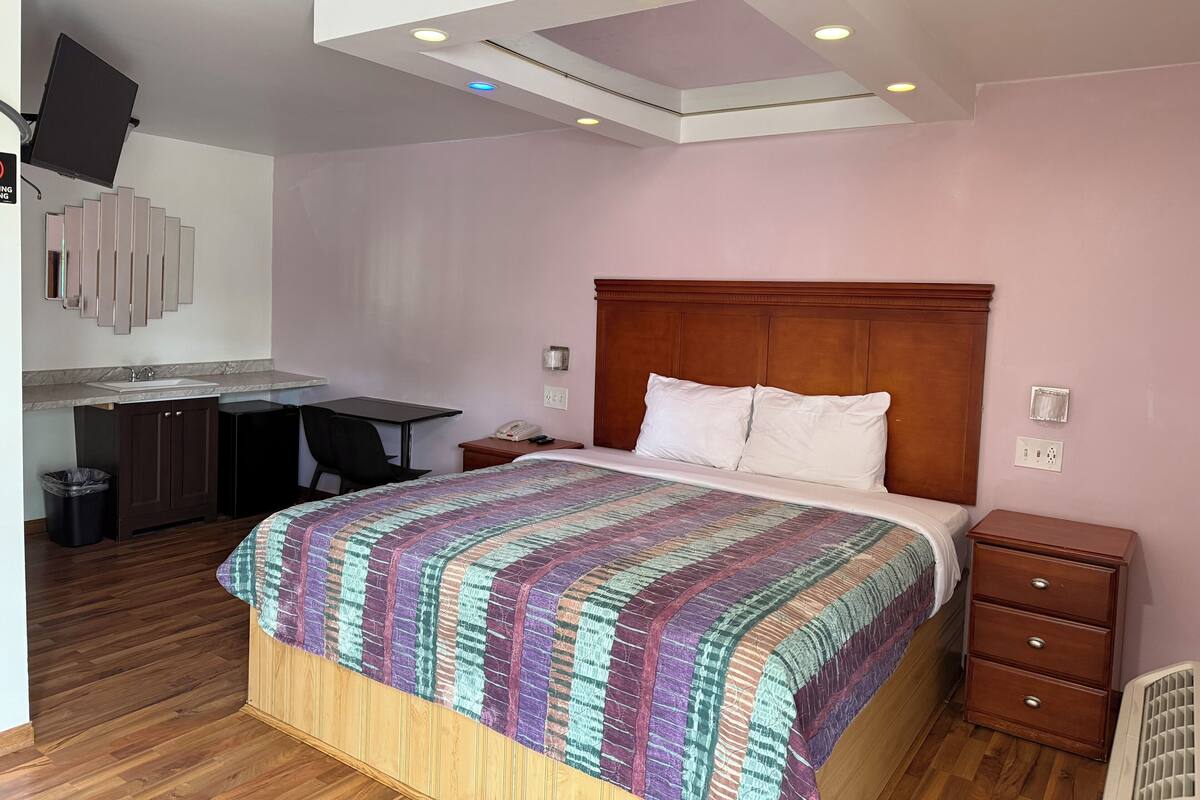 A bedroom with a bed, bedside table, and a desk with a chair.