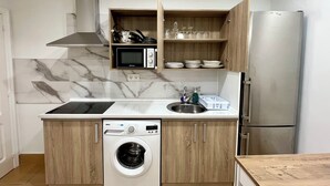 A compact kitchen with a built-in microwave, oven, and dishwasher. - Pensión Miramar (San Sebastian)