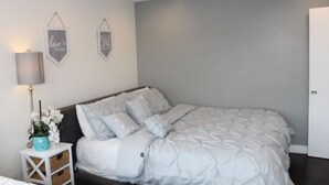 A bedroom with a large bed, a bedside table with a lamp, and two wall decorations. - perfect getaway. sf view. free parking on site (Oakland)