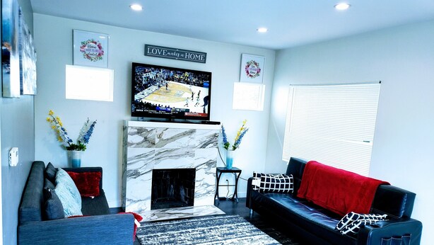 A modern living room with a fireplace, a flat-screen TV, and a black leather sofa. - perfect getaway. sf view. free parking on site (Oakland)