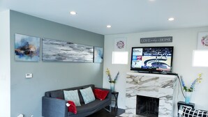 A modern living room with a grey couch, a fireplace, and abstract wall art. - perfect getaway. sf view. free parking on site (Oakland)