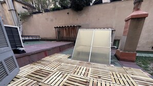 A patio area with wooden planks and a large glass door. - Large American Studio (Toulon)